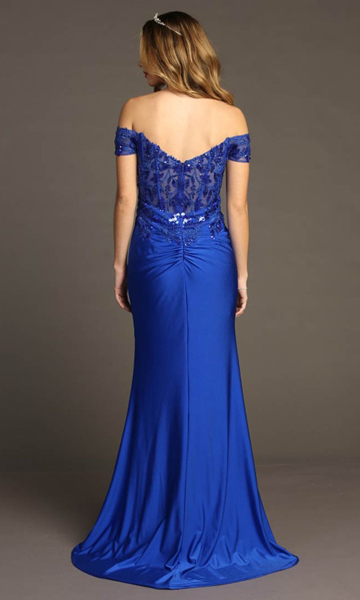 Woman models the Chicas YG5027 Sequin-Bodice Long Prom Dress, featuring an off-the-shoulder design, floor-length royal blue skirt, and sparkling sequin corset bodice, facing away from the camera against a plain background.